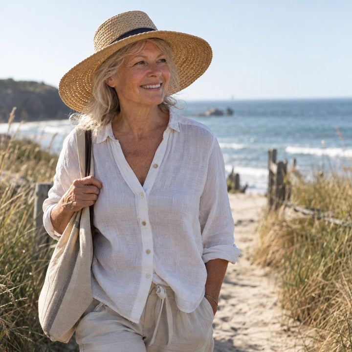 Woman in her sixties in a straw hat walking along a beach path
